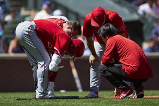 Los Angeles Angels designated hitter Shohei Ohtani is visited by trainers before.