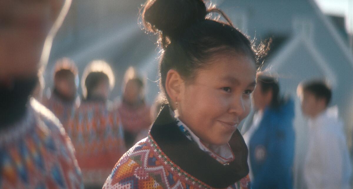 A smiling girl wears native Greenlandic clothing.