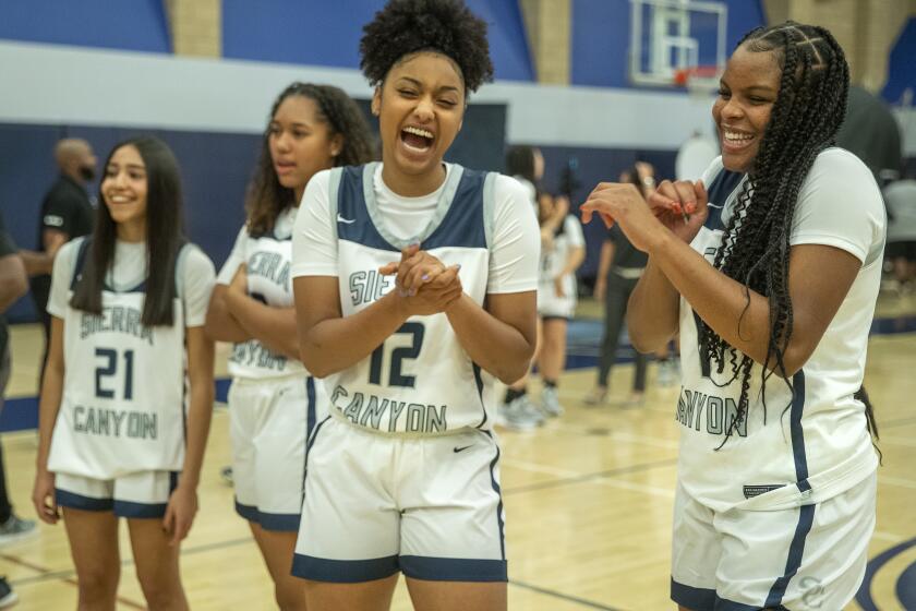 CHATSWORTH, CA - OCTOBER 27, 2021: Juju Watkins, foreground, left and Mac Randolph, right, members of the Sierra Canyon girls basketball team, share a light moment together during media day inside the school's gymnasium. (Mel Melcon / Los Angeles Times)