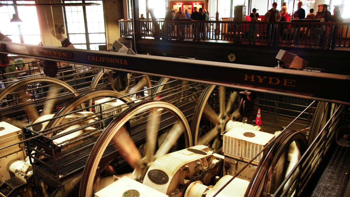 Visitors to the Cable Car Museum in San Francisco watch the big heavy metal wheels in the poerhouse while they turn and pull the cables.