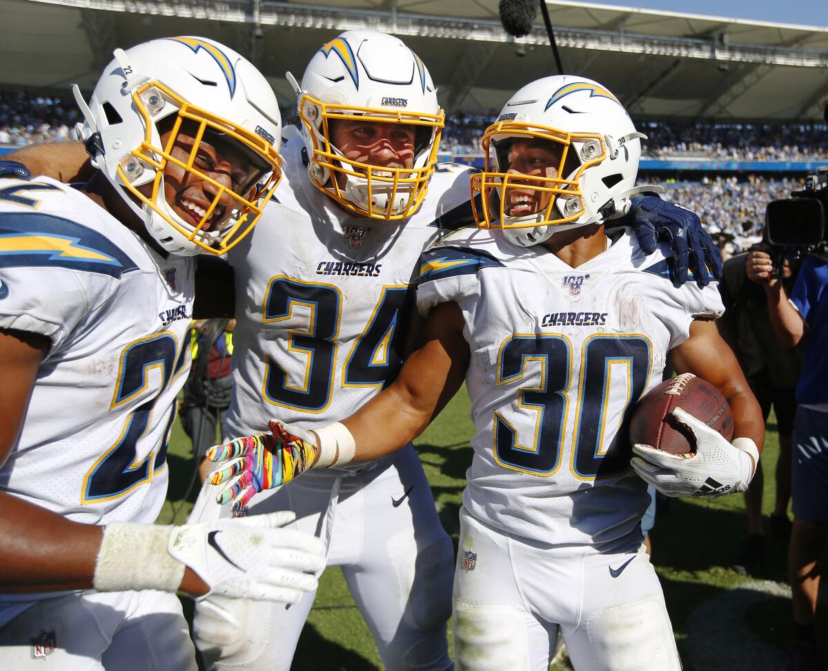 Los Angeles Chargers Austin Ekeler (30), right, celebrates his game-winning touchdown in overtime against the Indianapolis Colts with teammates Justin Jackson, left, and Derek Watt in Carson on Sept. 8, 2019.