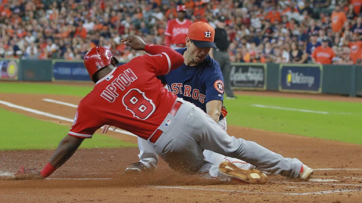 Astros pitcher Charlie Morton is late with the tag as Angels outfielder Justin Upton scores on a wild pitch in the first inning Sunday.