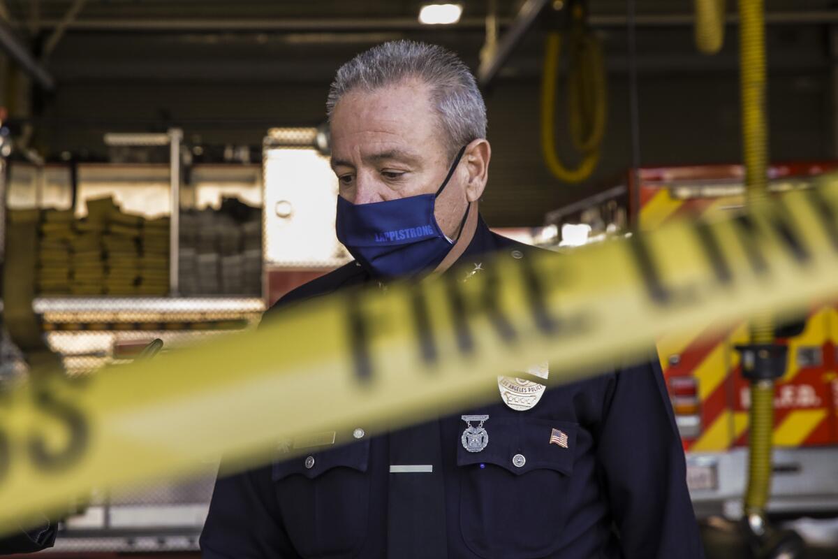 Los Angeles Police Chief Michel Moore wears a mask and speaks to reporters.
