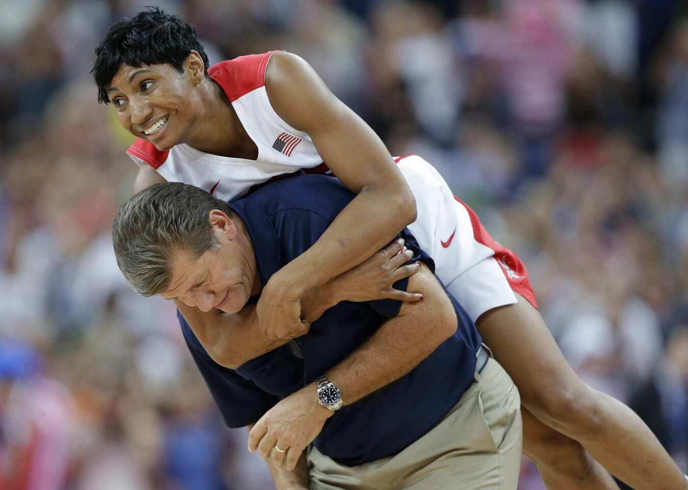 Angel McCoughtry jumps on the back of United States Coach Geno Auriemma after beating France, 86-50, in the women's gold-medal basketball game at the 2012 Summer Olympics.