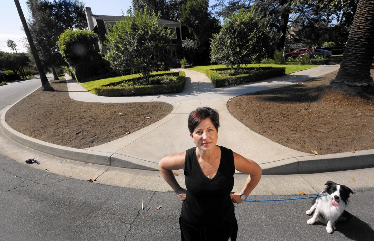 Tina House and her border collie Archie stand next to two parkways located in front of her home in Pasadena.