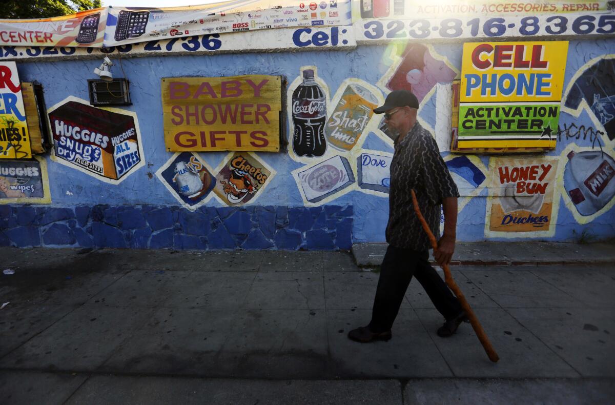 Murel Polee walks past a store at 94th and Figueroa streets in South Los Angeles where three children were caught in the crossfire of a shooting in front of a taco stand Wednesday night.