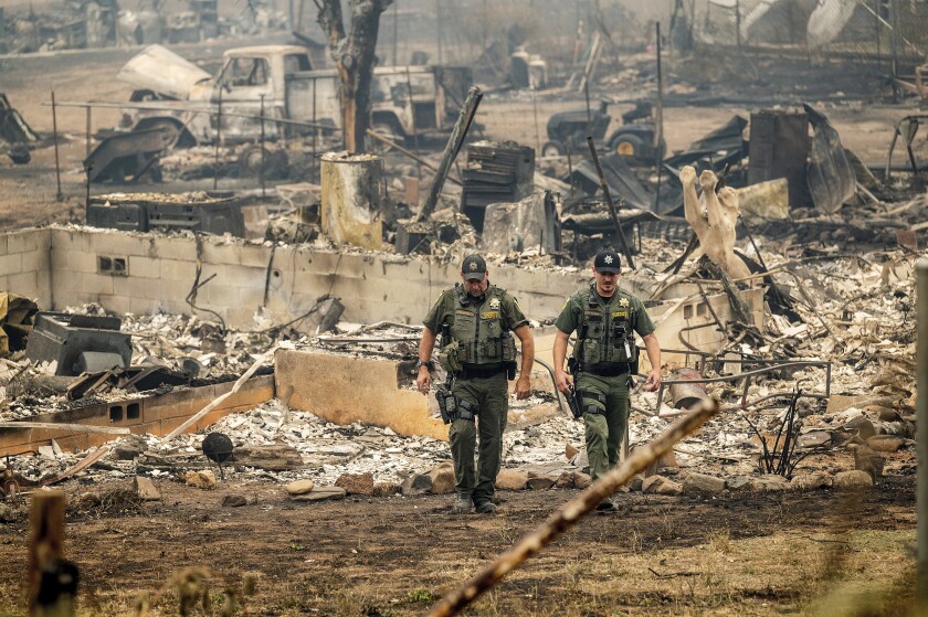 Sheriff's deputies walk away from the rubble of a home destroyed by the McKinney fire in Klamath National Forest