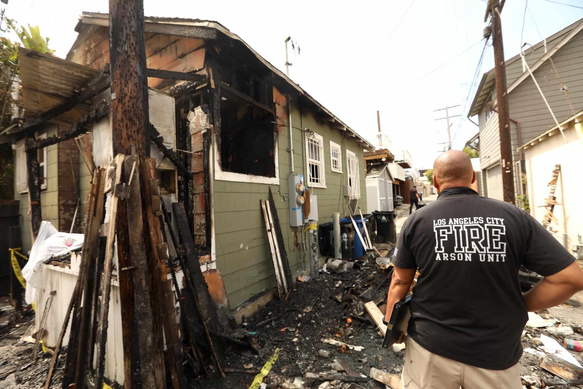 A fire investigator stands next to the remains of a house that was damaged in a fire