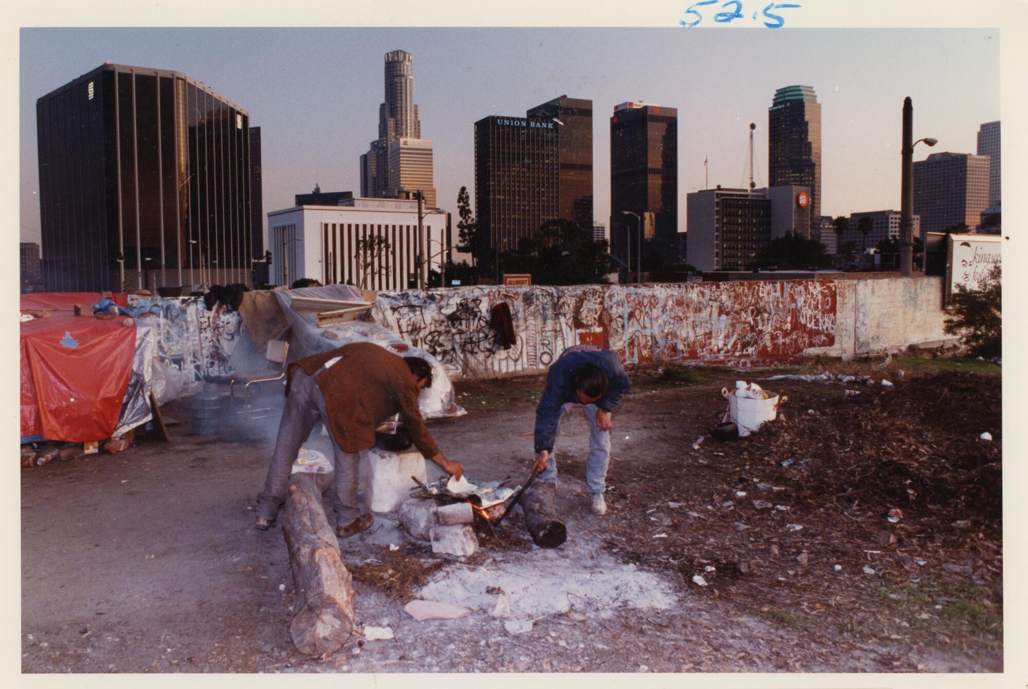 Two people prepare dinner on top of an office building that was halted from construction in February 1992.