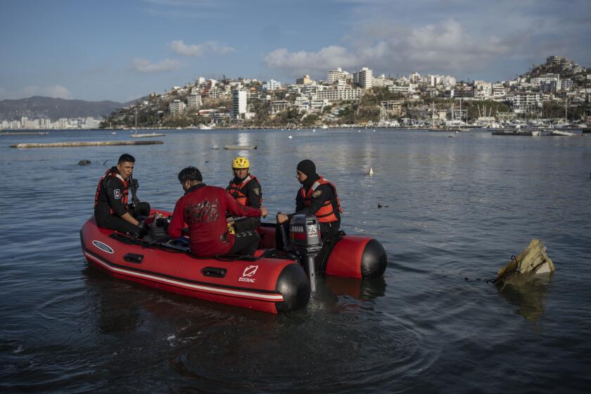 Firefighters and scuba divers search for bodies near sunken boats at a yacht club in Acapulco, Mexico, Saturday, Oct. 28, 2023, following Hurricane Otis. (AP Photo/Felix Marquez)