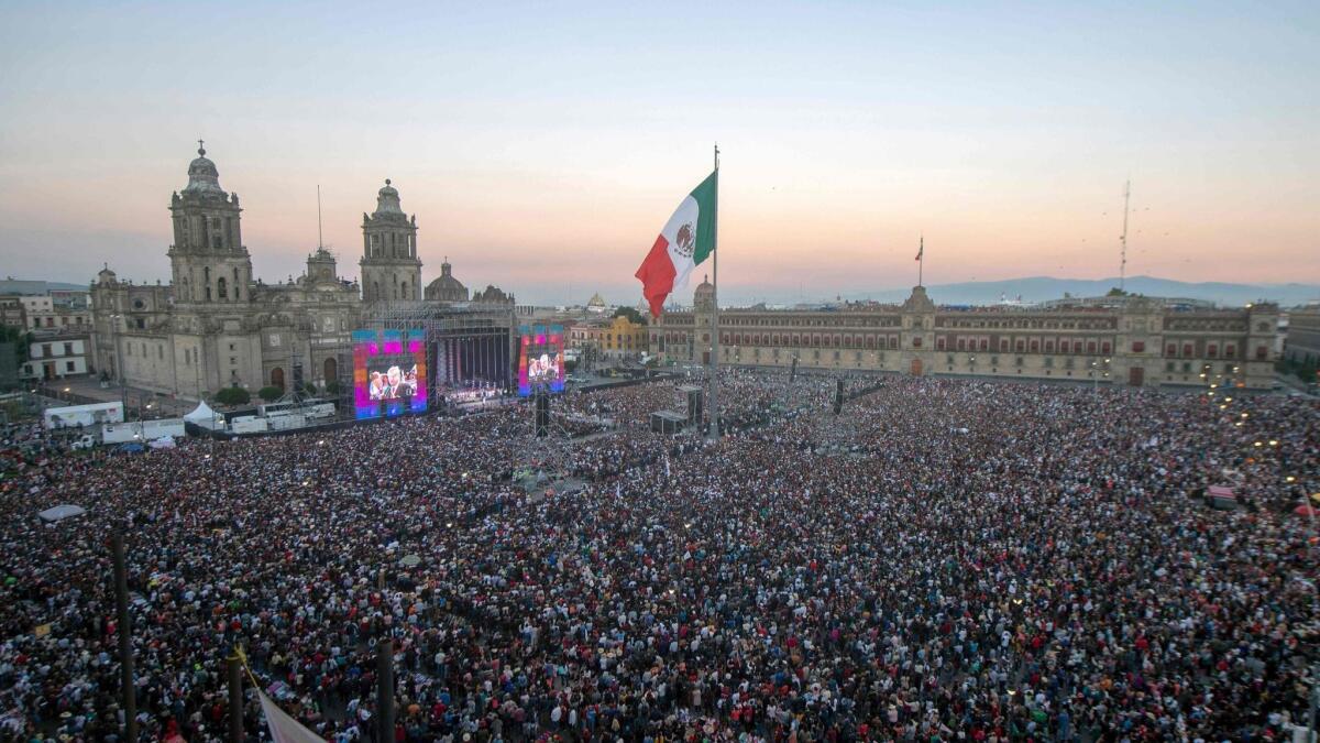 Supporters of Mexico's new president, Andres Manuel Lopez Obrador, watch his inauguration ceremony on a huge screen at the Zocalo square in Mexico City on Dec. 1, 2018.