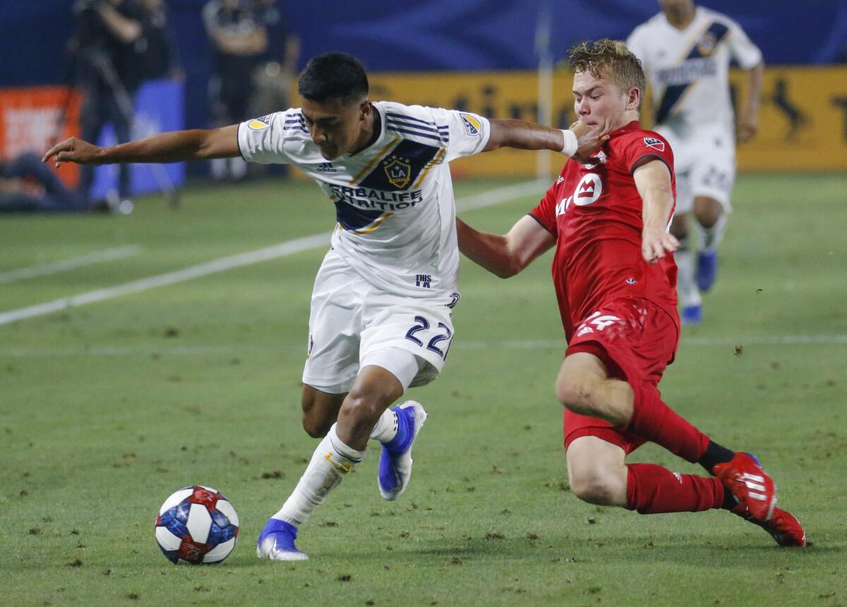 L.A. Galaxy defender Julian Araujo and Toronto FC midfielder Jacob Shaffelburg vie for the ball during an MLS soccer match.