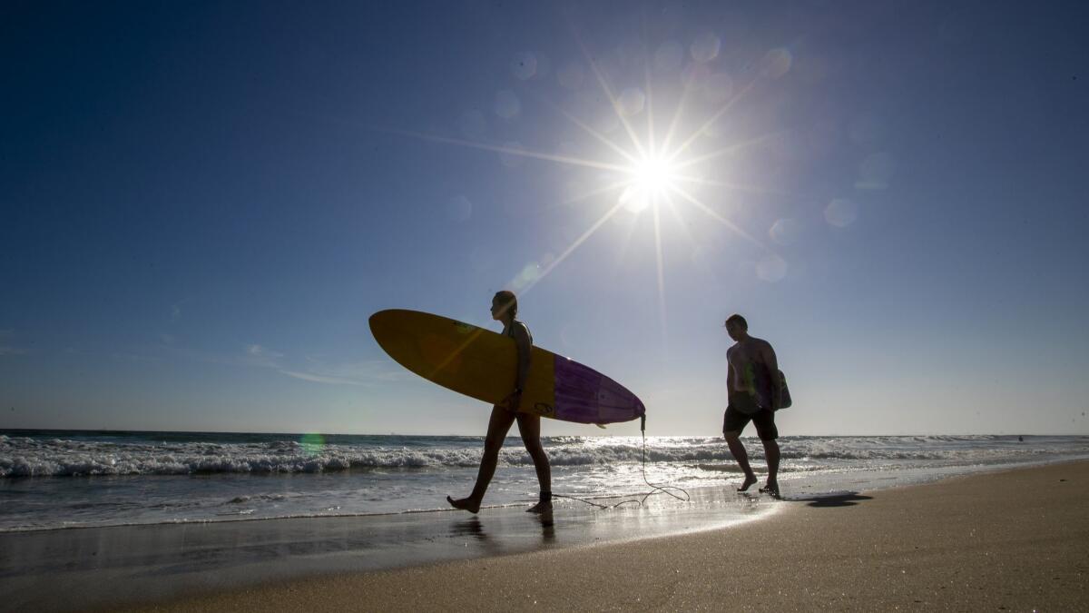 A surfer and a body boarder head out to catch some waves at Bolsa Chica State Beach in Huntington Beach on Tuesday.