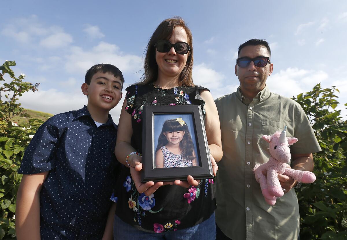 Joanna Valdivia holds a picture of daughter Sarah with son Ryan and husband Reyes at Tanaka Farms.