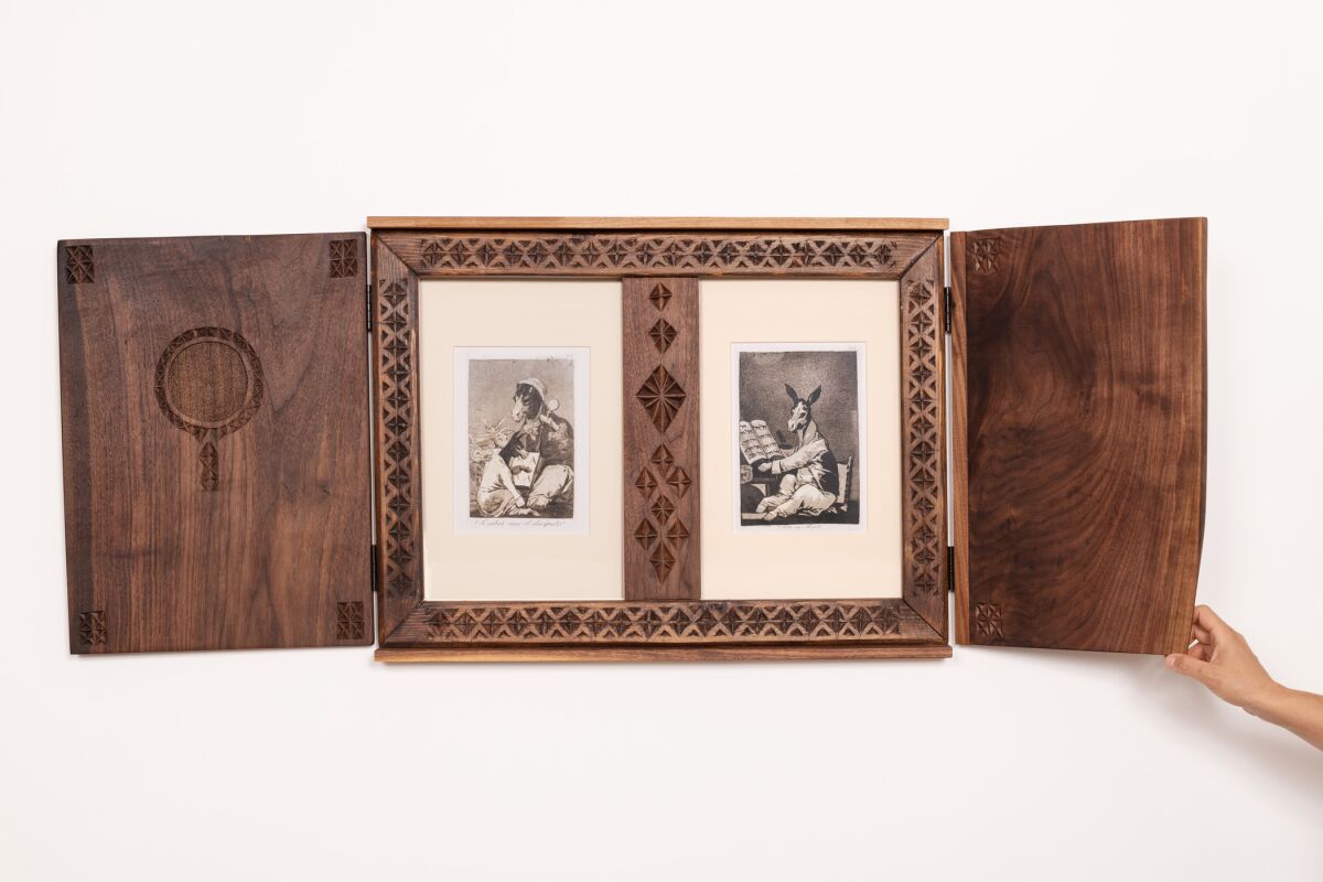 A triptych-style frame in dark, hand-tooled walnut features two prints by Goya showing donkeys
