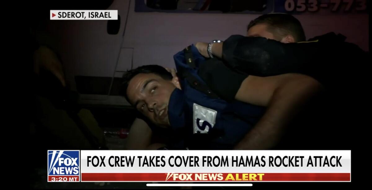 A TV news screen with the Chyron "Fox crew takes cover from Hamas rocket attack"