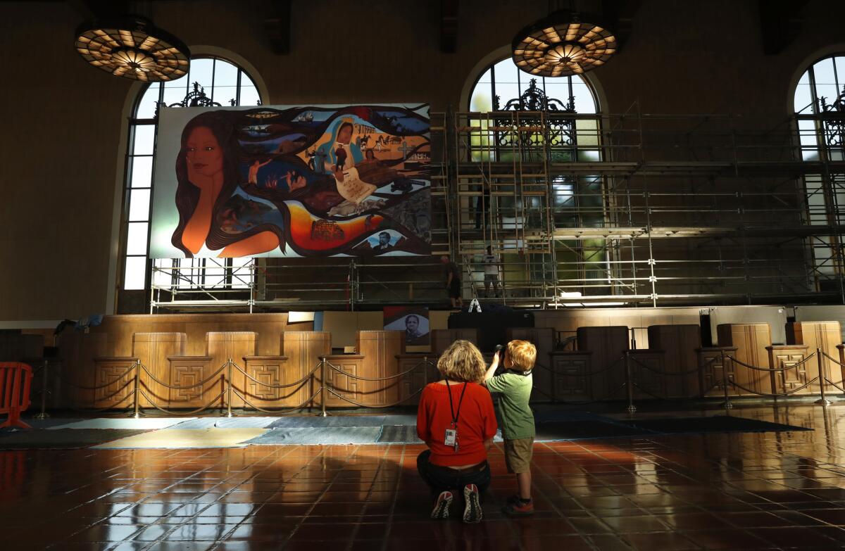 Co-curator Jessica Hough and her son Ansel, 4, pause to take in Barbara Carrasco's mural during its Union Station installation, which is now complete.