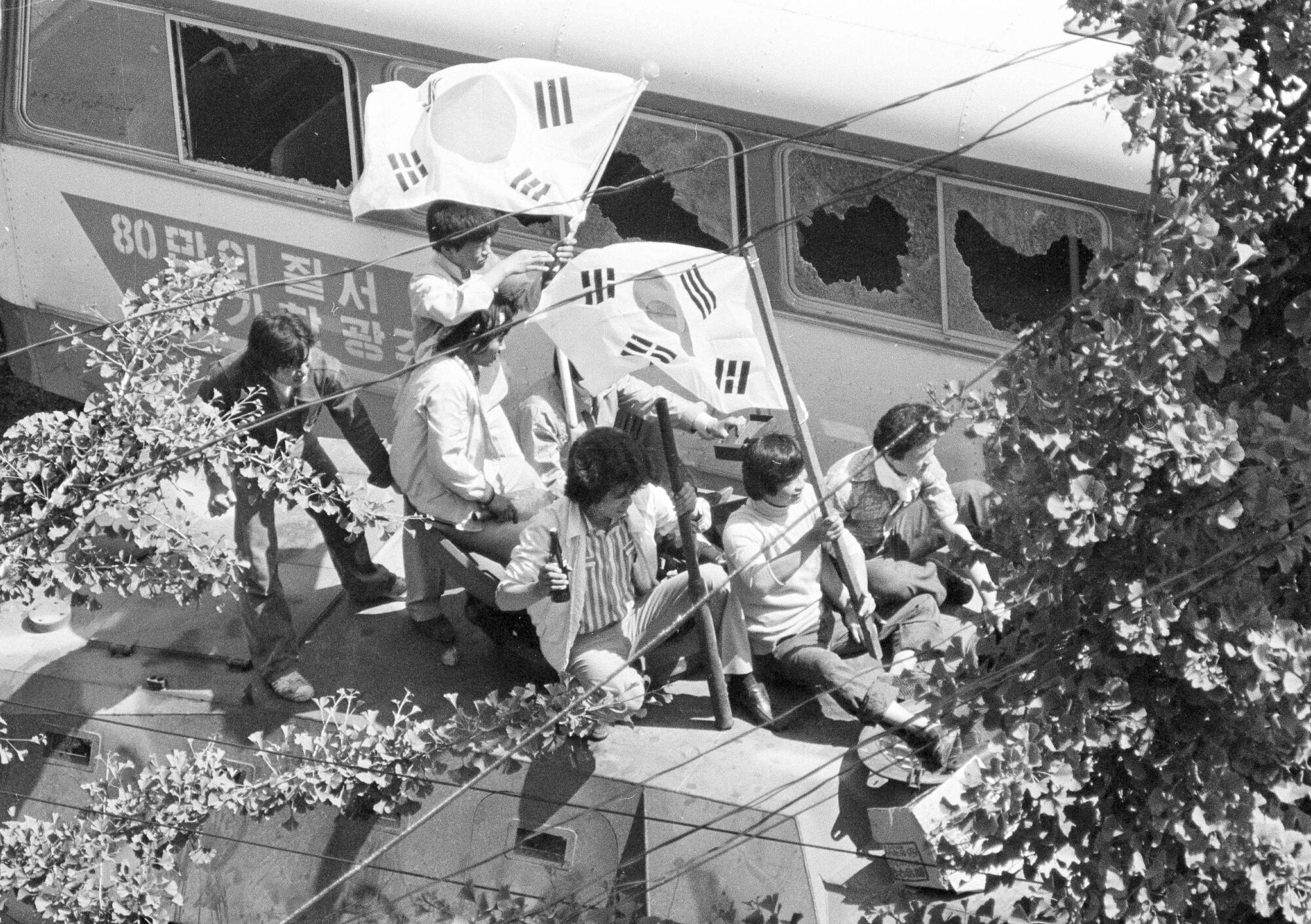 Anti-government protesters carrying South Korean flags sit behind a city bus used as a barricade