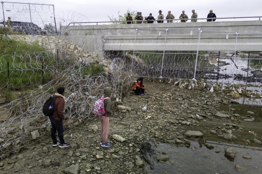 EAGLE PASS, TEXAS - MARCH 18: In an aerial view, U.S. soldiers and law enforcement officers stand over a small group of immigrants who had crossed the Rio Grande into the United States on March 18, 2024 in Eagle Pass, Texas. Texas National Guard troops have fortified the U.S.-Mexico border at Eagle Pass with vast amount of razor wire as part of Governor Greg Abbott's "Operation Lone Star" to deter migrants from crossing into Texas. The U.S. southwestern border with Mexico stretches nearly 2,000 miles, from the Gulf of Mexico to the Pacific Ocean and is marked by fences, deserts, mountains and the Rio Grande, which runs the entire length of Texas. Border and immigration issues have become dominant themes in the U.S. presidential election campaign. (Photo by John Moore/Getty Images)