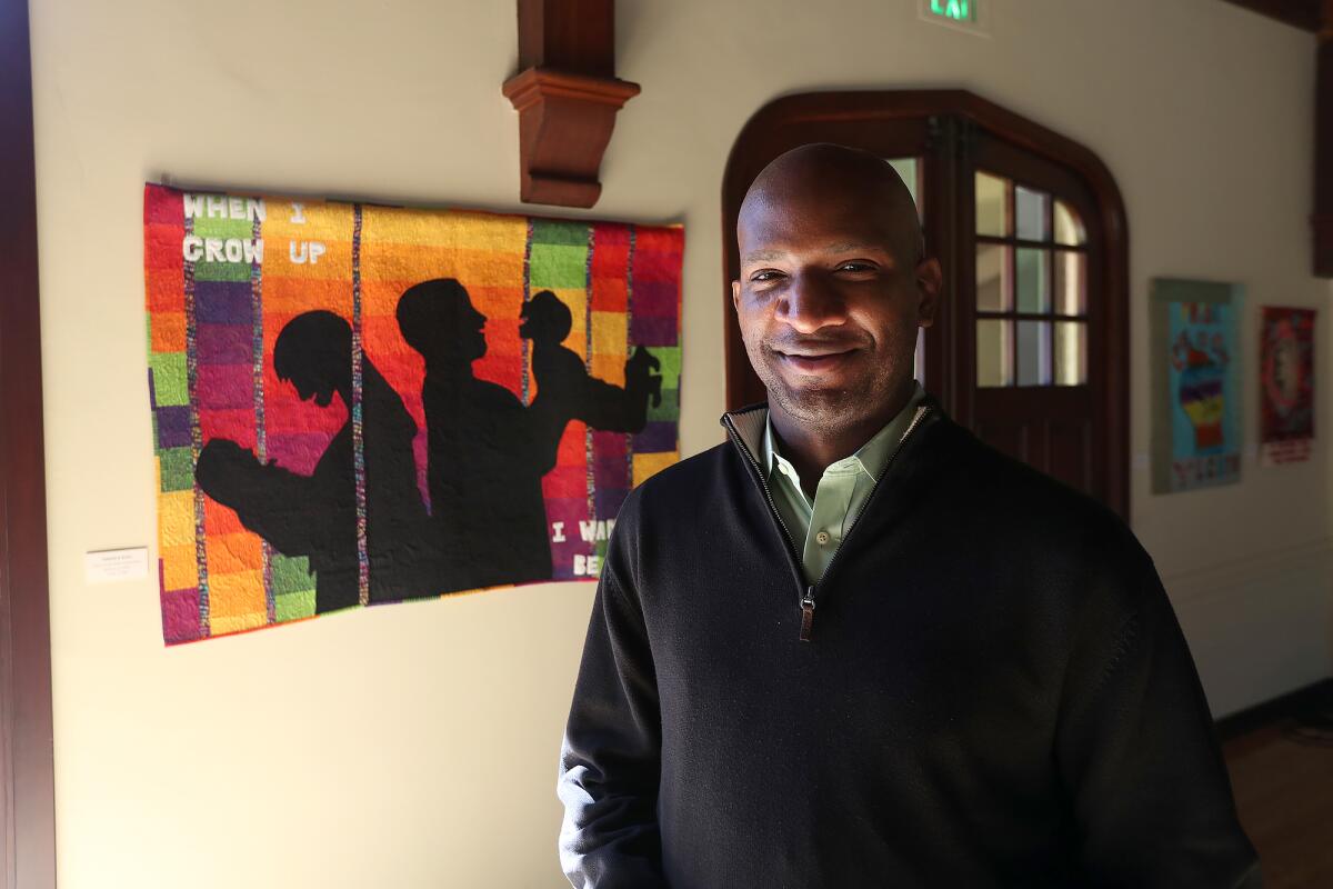 The Rev. Rodrick Echols stands next to one of Allyson Allen's "Piece-ful Protest" quilt works. 