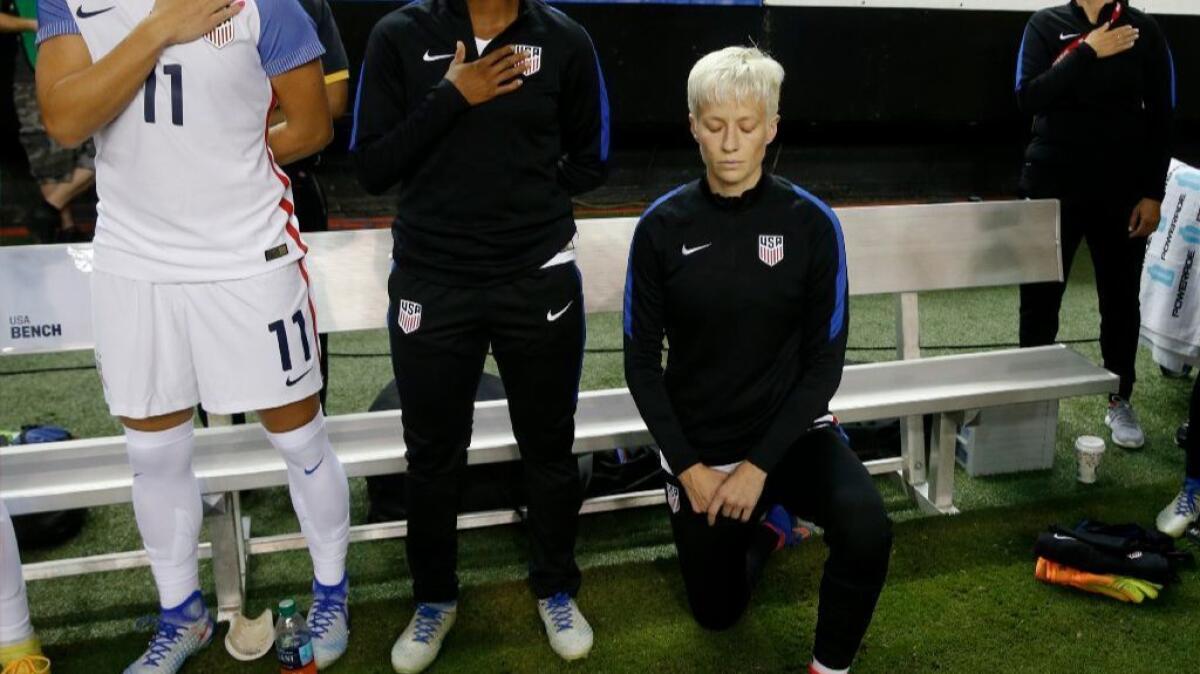 United States midfielder Megan Rapinoe kneels next to teammates as the U.S. national anthem is played before an exhibition soccer match on Sept. 18, 2016.