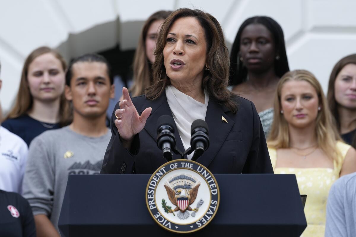 Vice President Kamala Harris speaks as young women stand behind her.