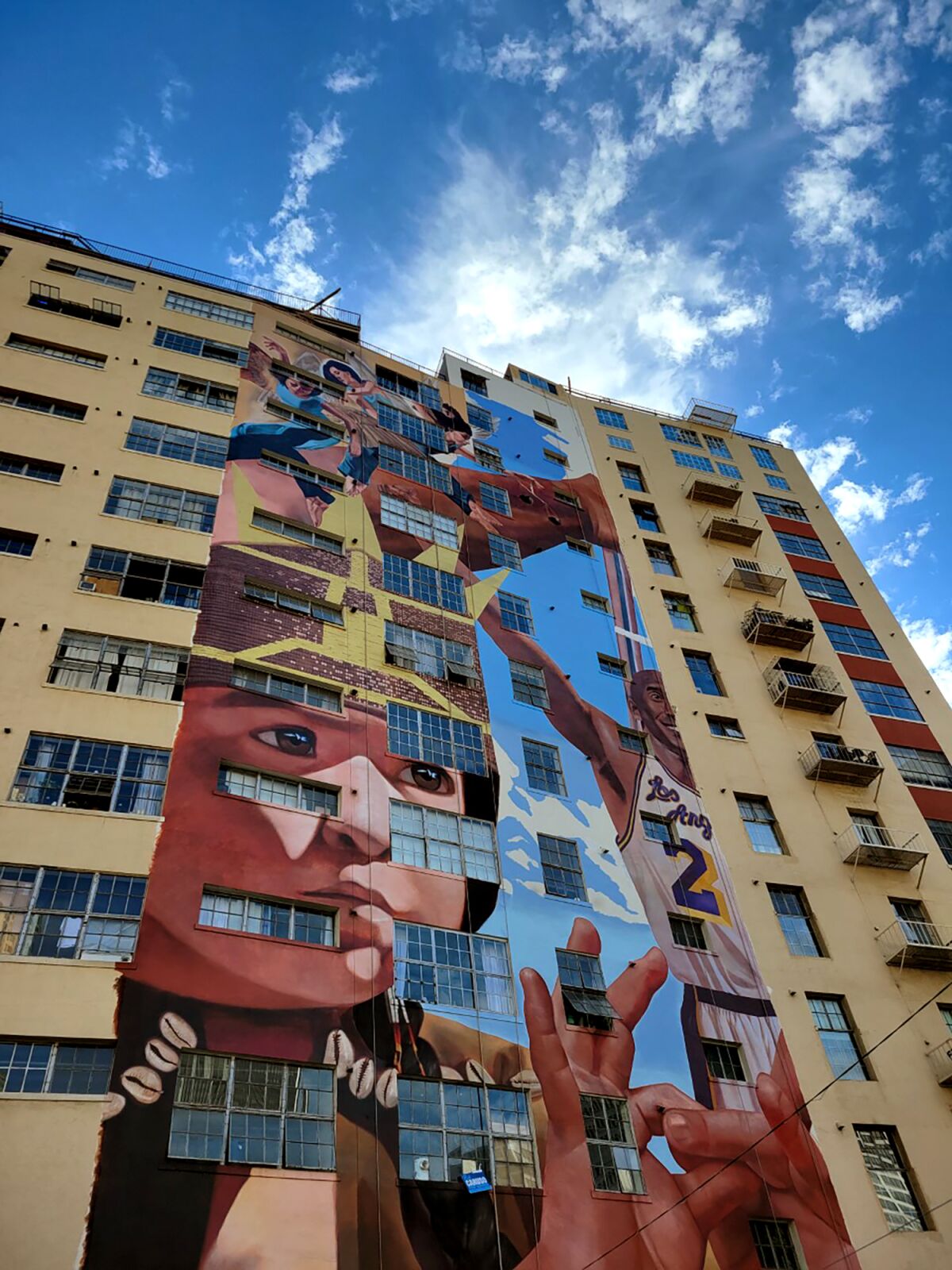 A portion of a mural painted on a tall building.
