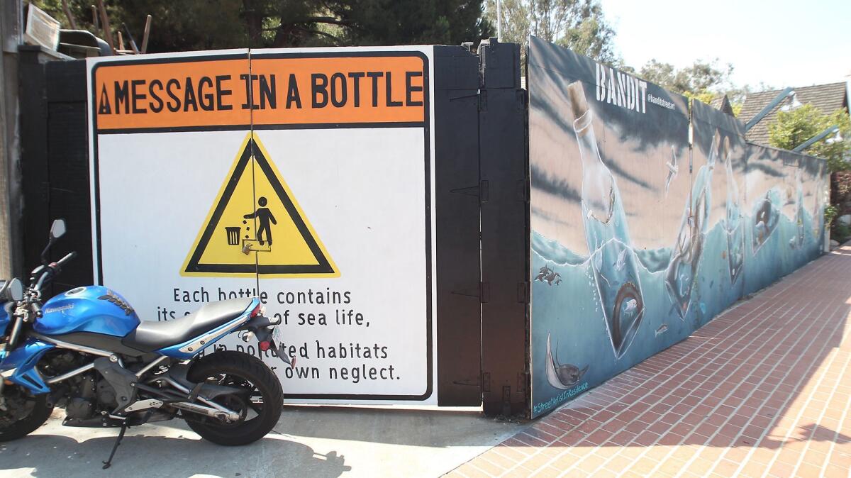 Street artist Bandit and producer Adam Casper collaborated on this mural, "Message in a Bottle," on a fence outside the Sawdust Festival in Laguna Beach. It depicts bottles containing marine life and symptoms of pollution.