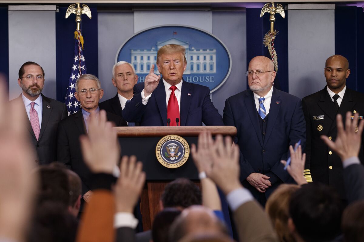 On Feb. 29 President Trump is in the press briefing room at the White House while surrounded by officials.