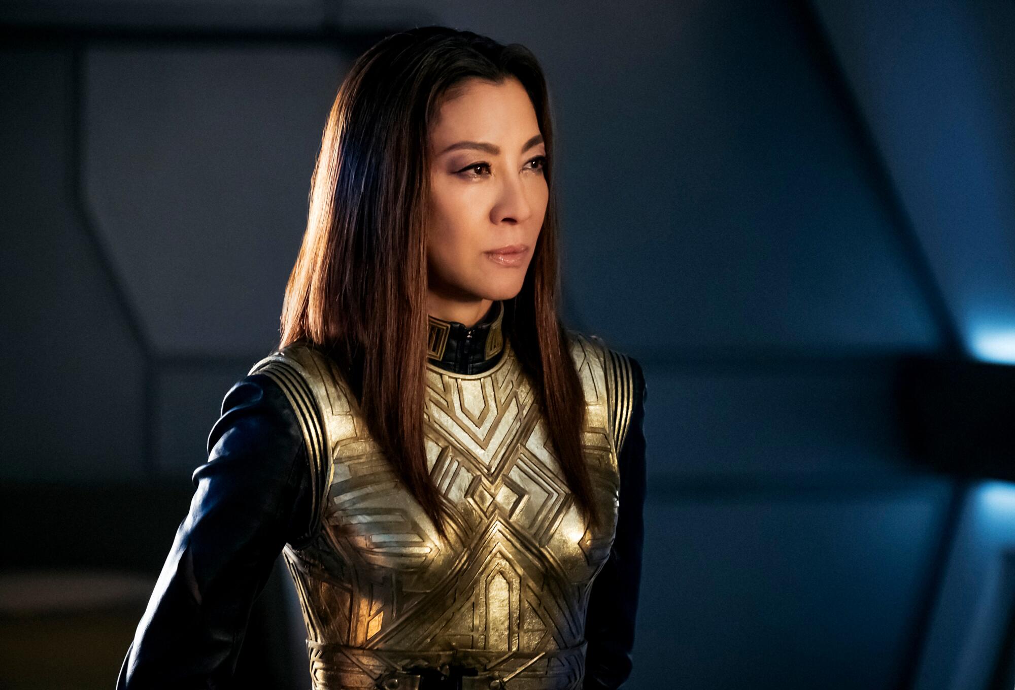 A woman with long brown hair in gold-plated chest armor.