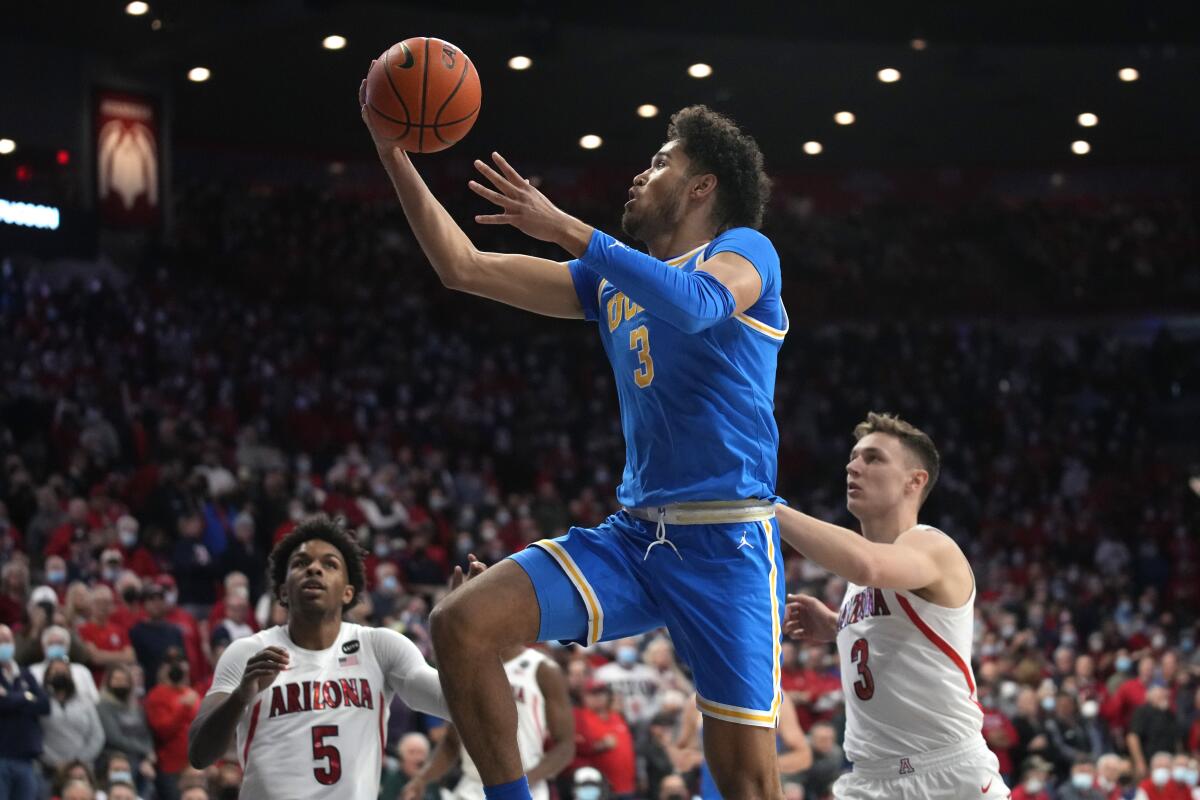 UCLA guard Johnny Juzang drives past Arizona guards Justin Kier and Pelle Larsson.