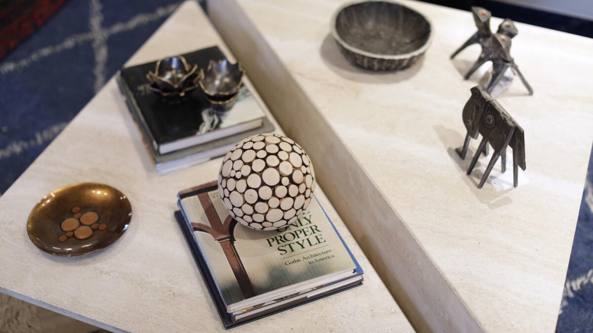 A 1970s travertine triangle table with books and tchotchkes on it