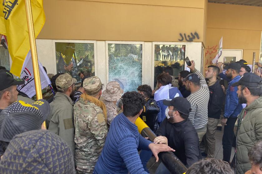 Protesters smash a window inside the U.S. embassy compound in Baghdad on Tuesday.
