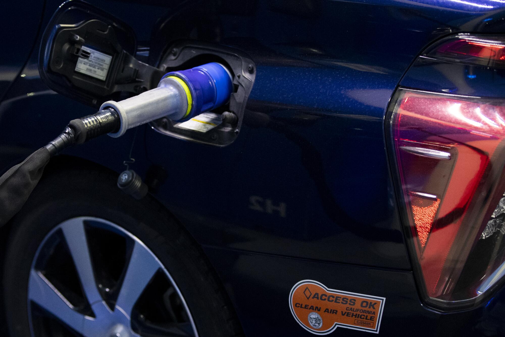 Hydrogen fuel cell car filling up at a station.