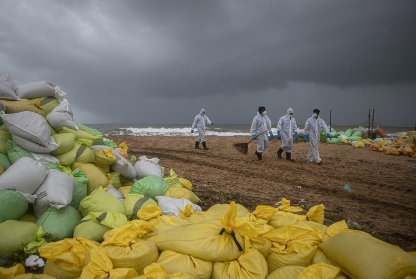 Sri Lankan navy soldiers walk on the beach looking for plastic debris washed ashore from fire damaged container ship MV X-Press Pearl at Kapungoda, on the outskirts of Colombo, Sri Lanka. Monday, June 14, 2021. (AP Photo/Eranga Jayawardena)