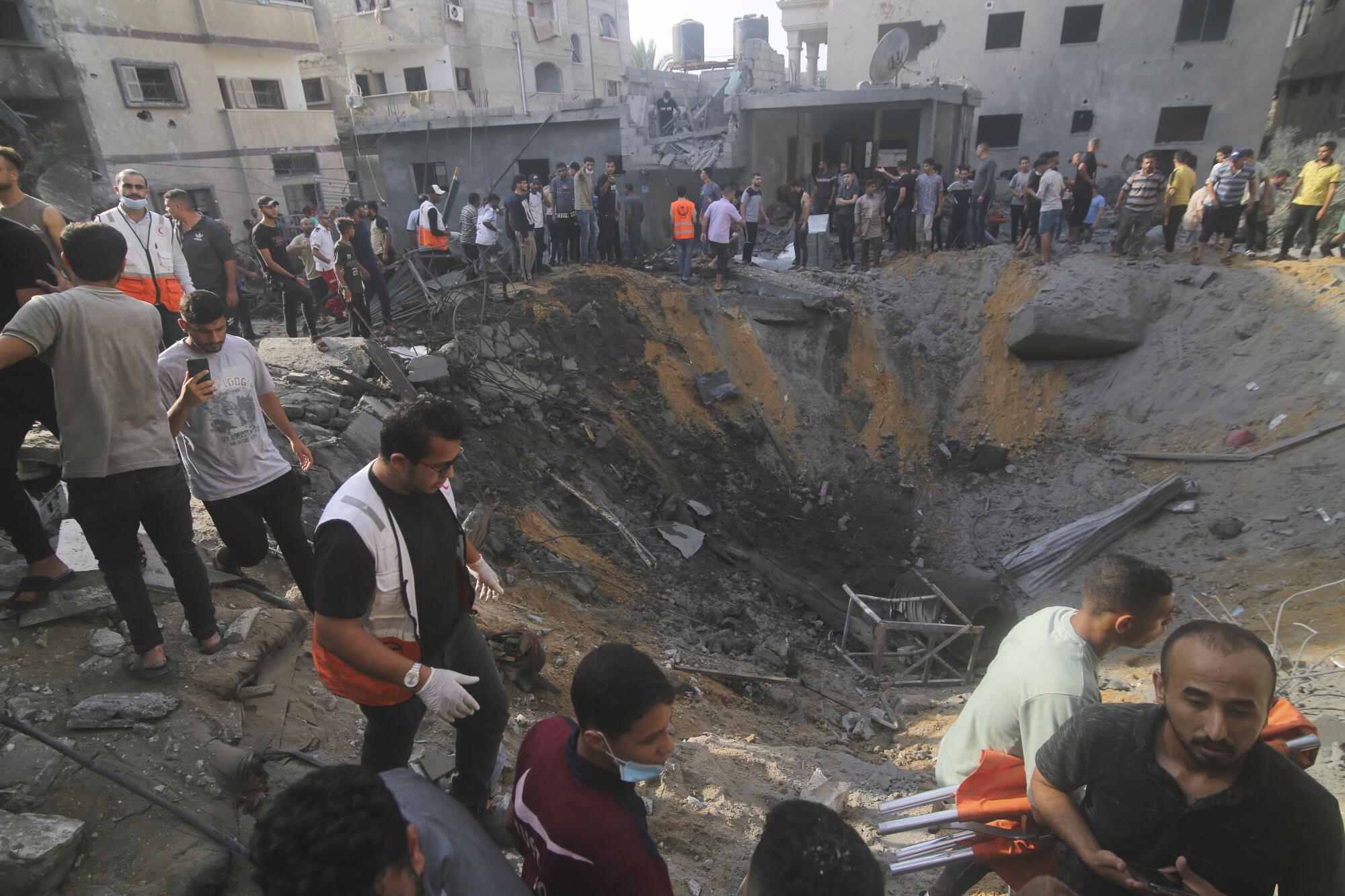 People by a large crater looking for survivors of an Israeli airstrike on Gaza