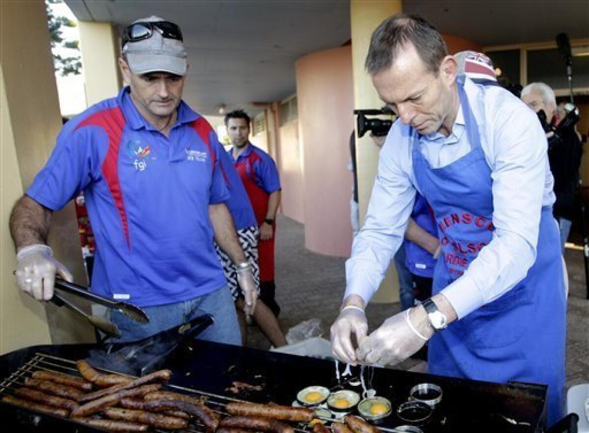 Australia's opposition leader Tony Abbott, right, cracks eggs on a hot plate while helping out at an election day sausage sizzle on Queenscliff Beach in Sydney, Australia, Saturday, Aug. 21, 2010. Australians go to the polls Saturday to vote in the federal election. (AP Photo/Rob Griffith)