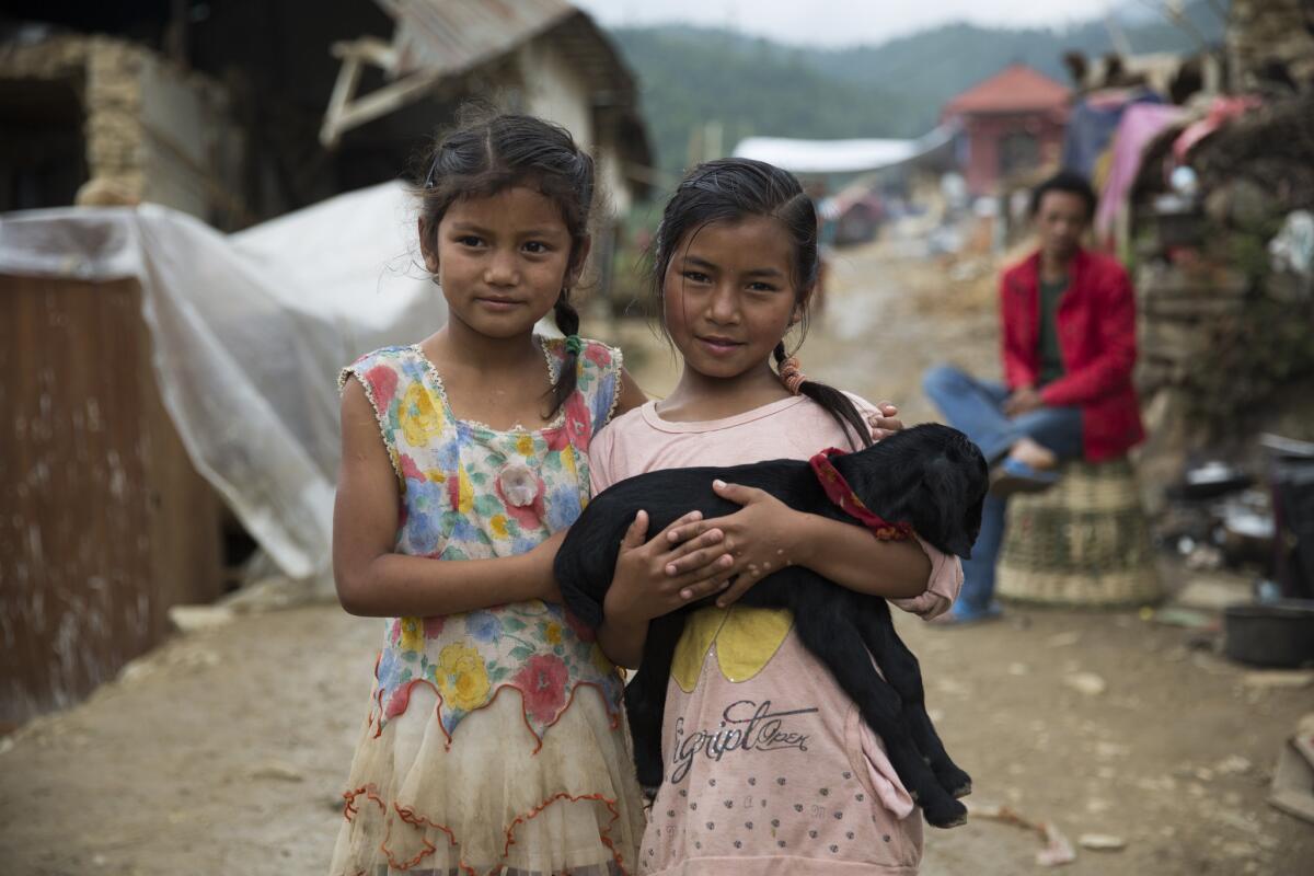 Two girls -- Dipika, left, and Susila -- hold a family goat in Pahade Thapa Gaon, an agricultural village outside Katmandu where the Humane Society International has deployed emergency animal welfare aid.