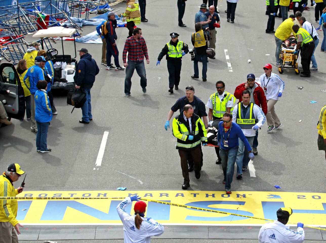 Medical workers take the injured across the finish line after explosions at the Boston Marathon.