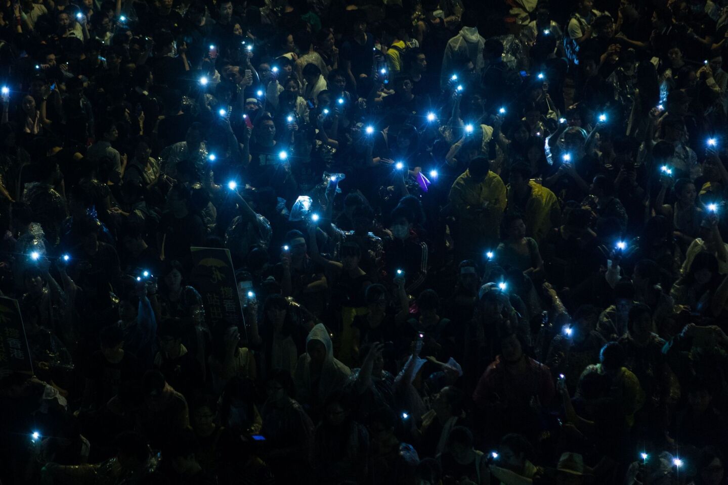 Pro-democracy protesters hold up their mobile phones after heavy rain in Hong Kong.