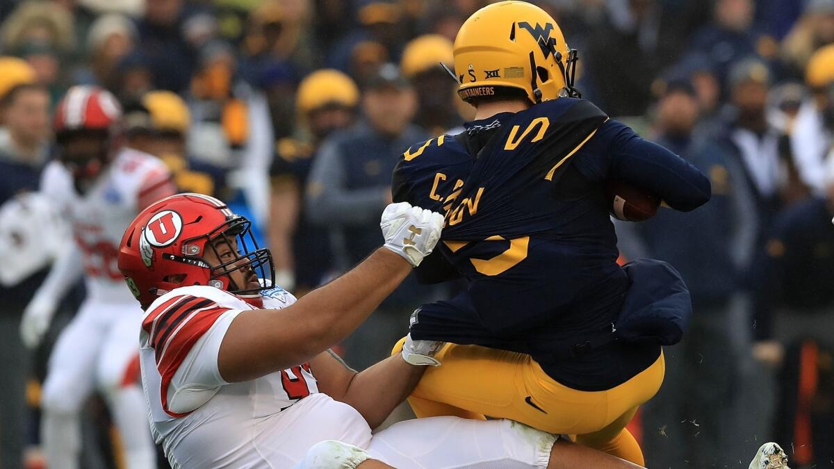 West Virgnia's Chris Chugunov (5) is sacked by Utah's Lowell Lotulelei (93) in the second quarter during Zaxby's Heart of Dallas Bowl on Tuesday.