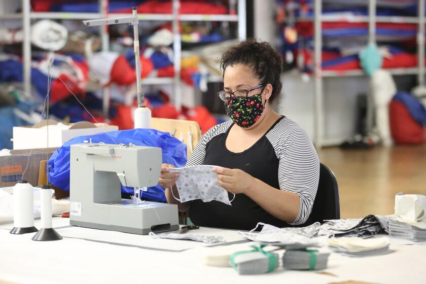 Gabriela Garcia sews the second part of a face covering at the Ullman Sails workshop headquarters in Santa Ana.