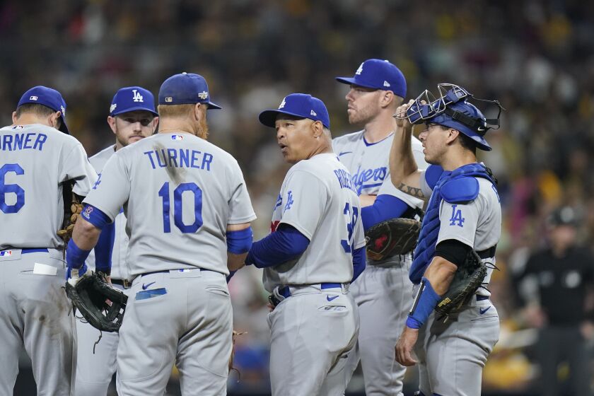 Los Angeles Dodgers manager Dave Roberts, center, meets with players on the mound during the fourth inning in Game 3 of a baseball NL Division Series against the San Diego Padres, Friday, Oct. 14, 2022, in San Diego. (AP Photo/Jae C. Hong)