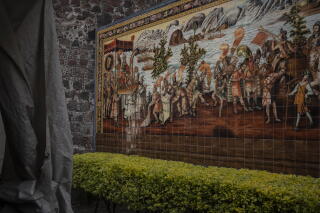 A mural of several people in patterned outfits next to a stone wall