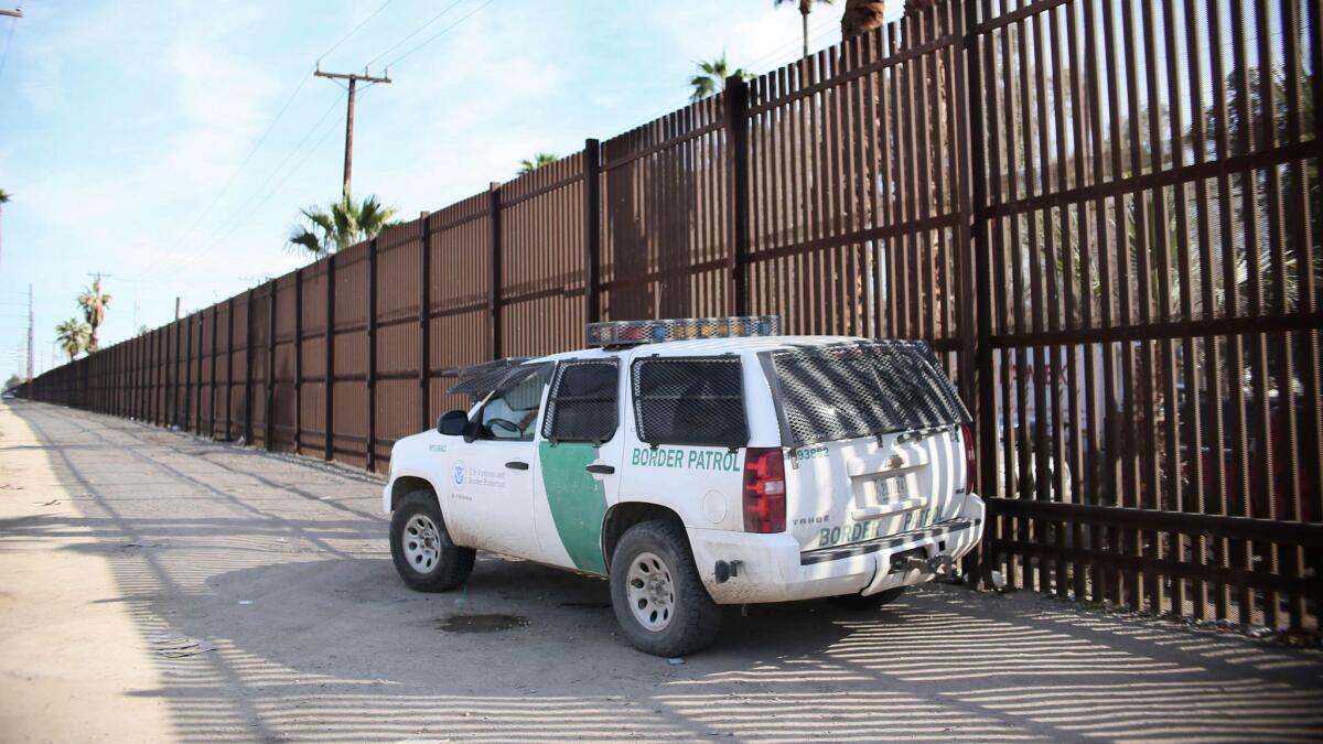 A Border Patrol agent looks over the U.S.-Mexico border wall in Calexico, Calif.