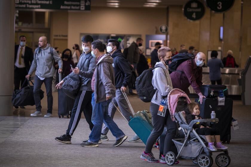 Santa Ana, CA - December 21: Travelers arrive for Christmas and holiday travel, although some people cancelling or rethinking their holiday travel plans because of the omicron variant at John Wayne Airport in Santa Ana, CA on Tuesday, Dec. 21, 2021. (Allen J. Schaben / Los Angeles Times)