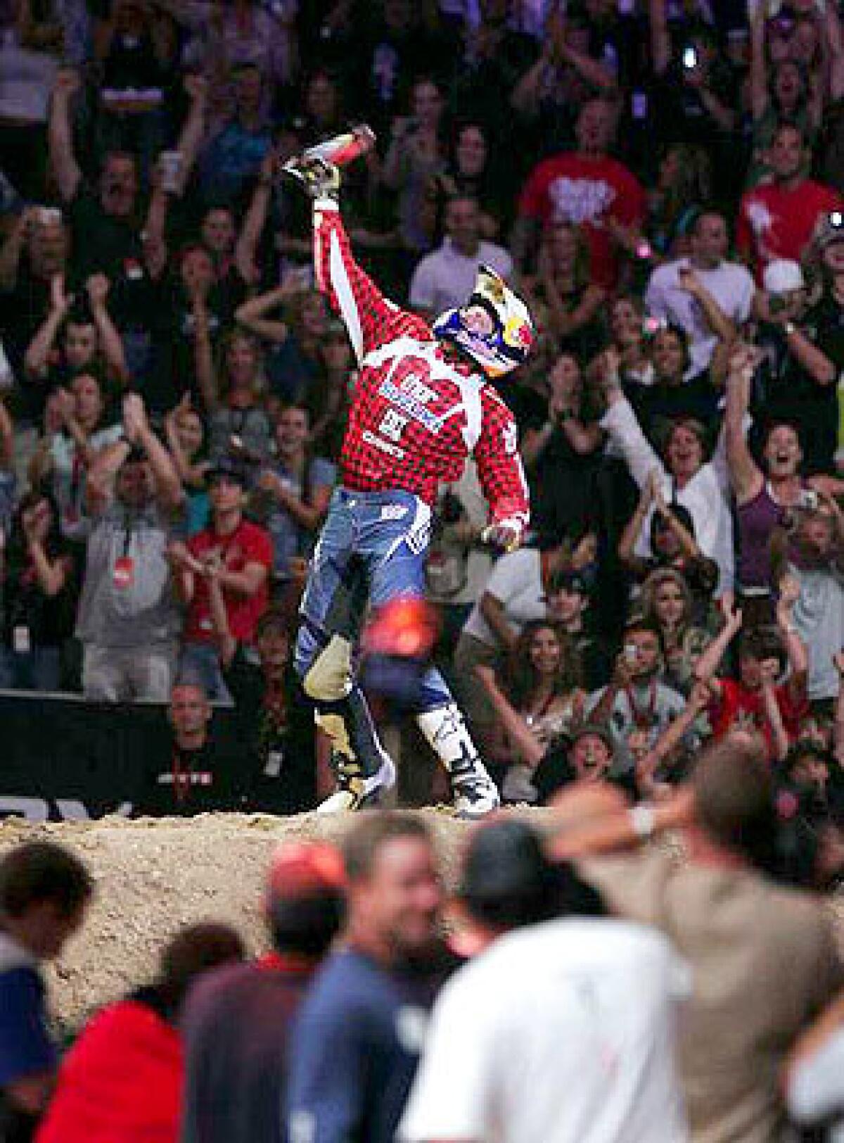 Travis Pastrana celebrates along with the crowd at Staples Center after executing a double back flip during the Moto X best trick final of X Games 12.