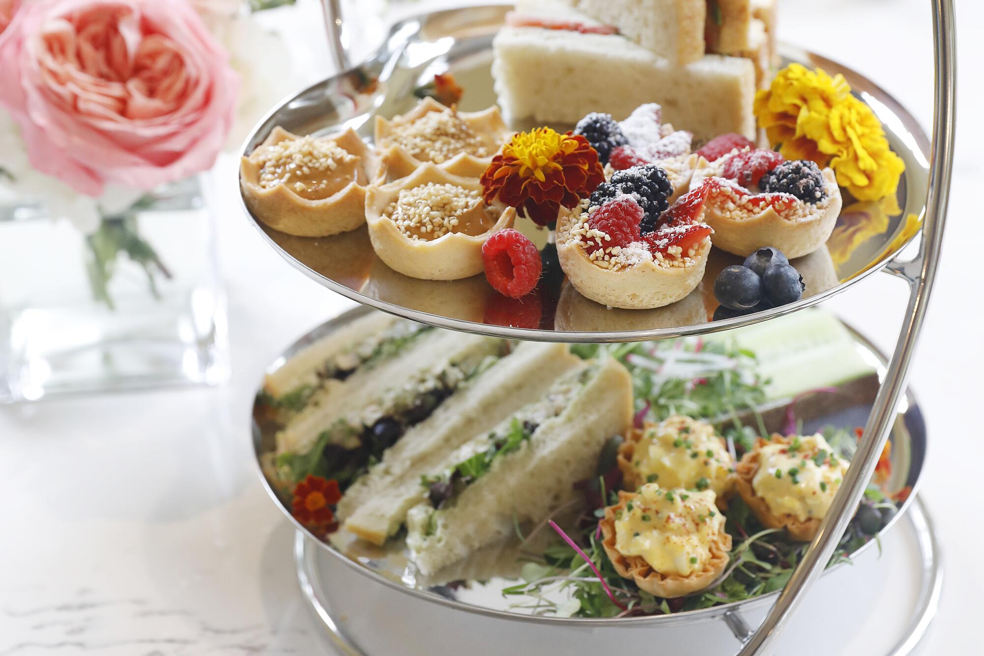 A three-tied tower of finger sandwiches and other treats graces a table in the renovated Huntington tea room. 