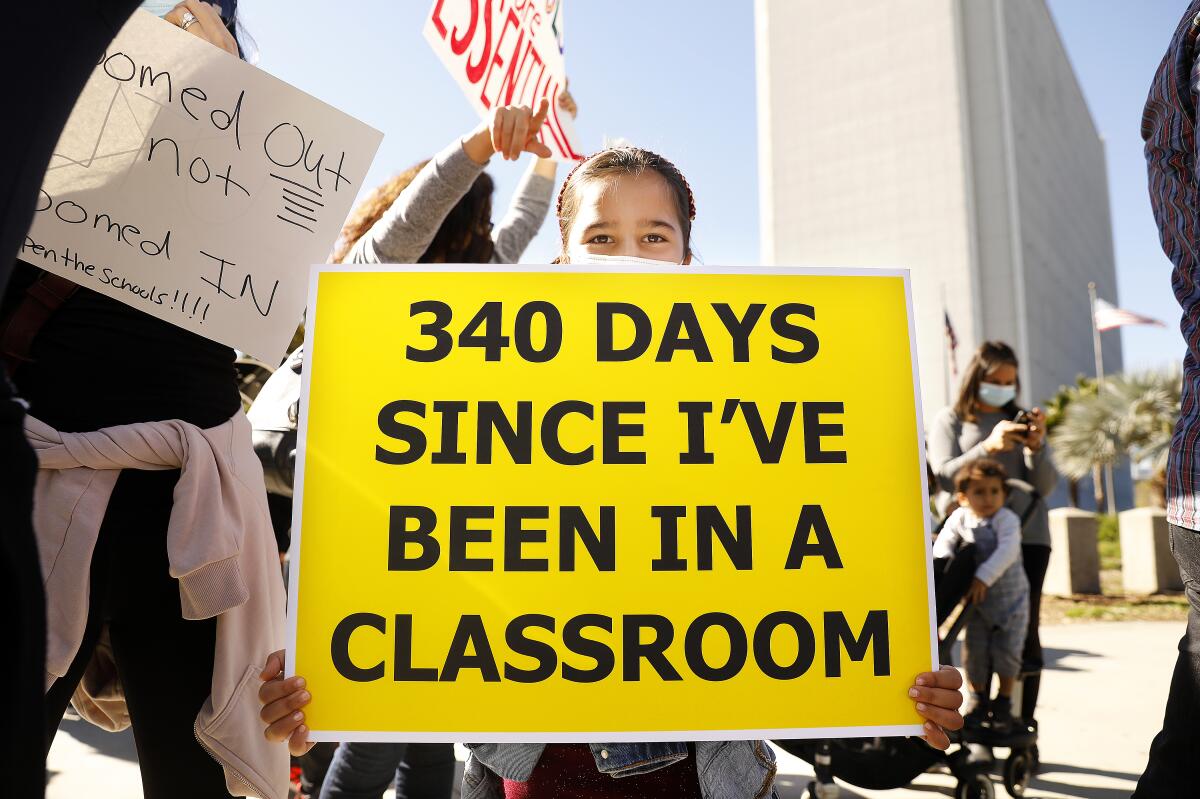 A kid holding a sign that says "340 days since I've been in a classroom"