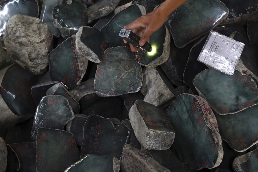 FILE - A merchant examines a jade stone displayed at the Gems Emporium in Naypyitaw, Myanmar on Nov. 13, 2018. Human rights activists are lobbying major jewelers to stop buying gems sourced in Myanmar as a way to exert pressure on Myanmar’s military leaders by limiting profits from the country’s lucrative mining industry. (AP Photo/Aung Shine Oo, File)